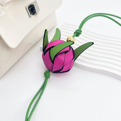 Colorful dragon fruit shaped leather accessory displayed next to white handbag