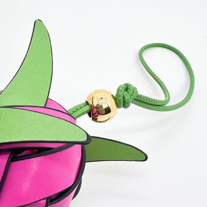Pink and green dragon fruit leather charm hanging on a white handbag