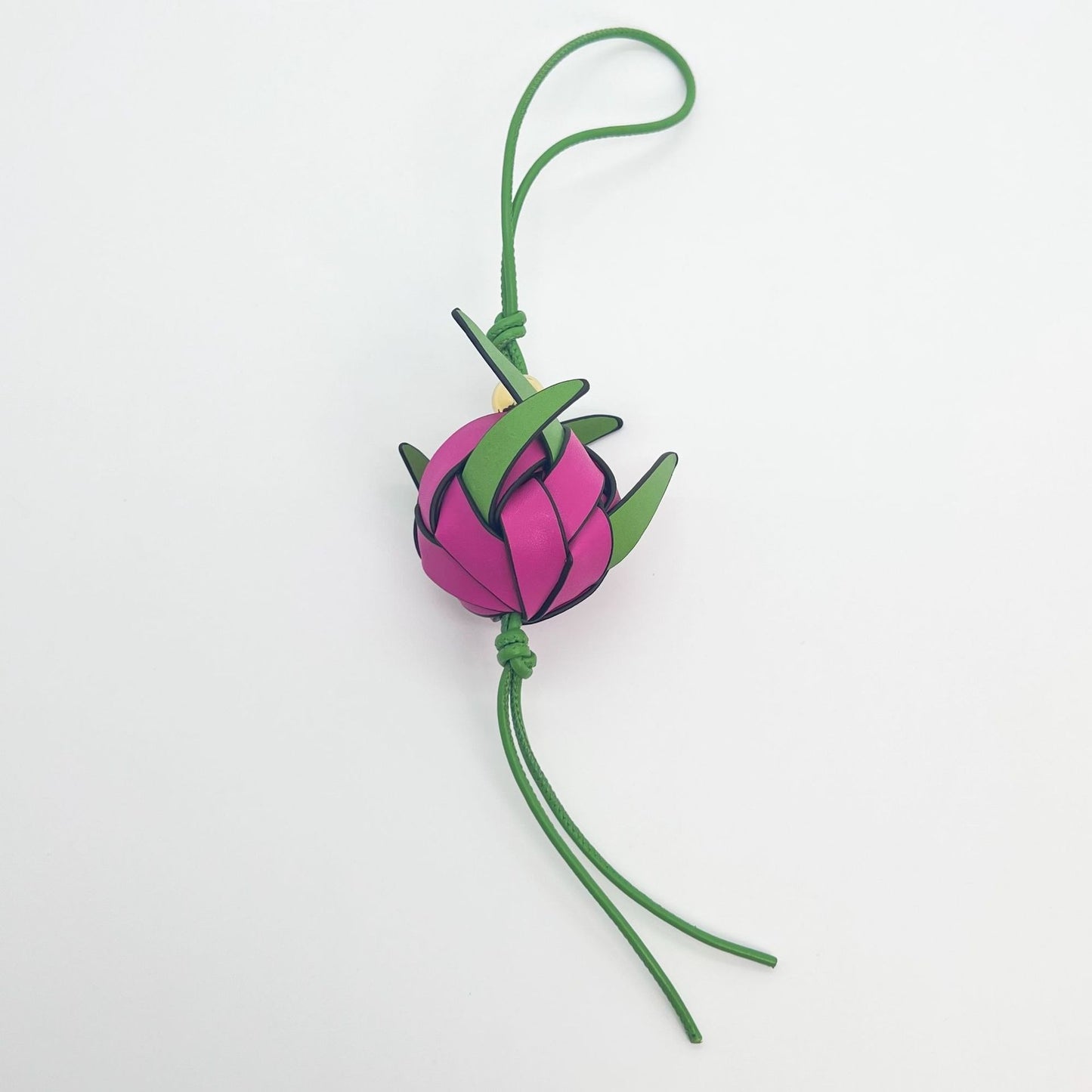 Close-up of leather dragon fruit bag charm with green loop and gold bead