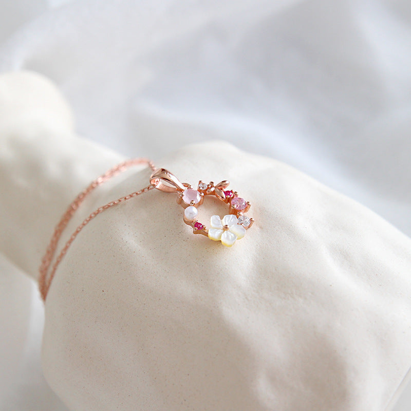 Close-up of rose gold flower pendant necklace displayed on soft fabric, ideal for minimalist jewelry wholesale and boutique gift collections