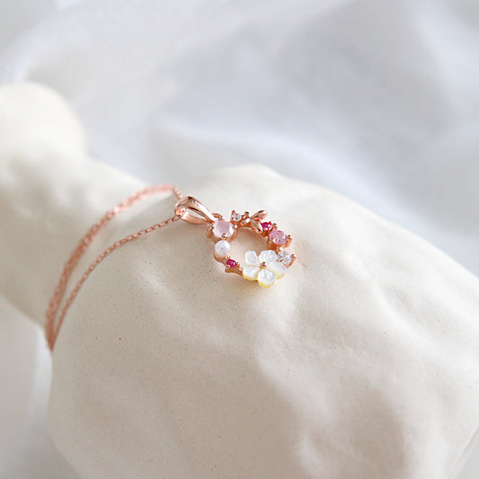 Close-up of rose gold flower pendant necklace displayed on soft fabric, ideal for minimalist jewelry wholesale and boutique gift collections