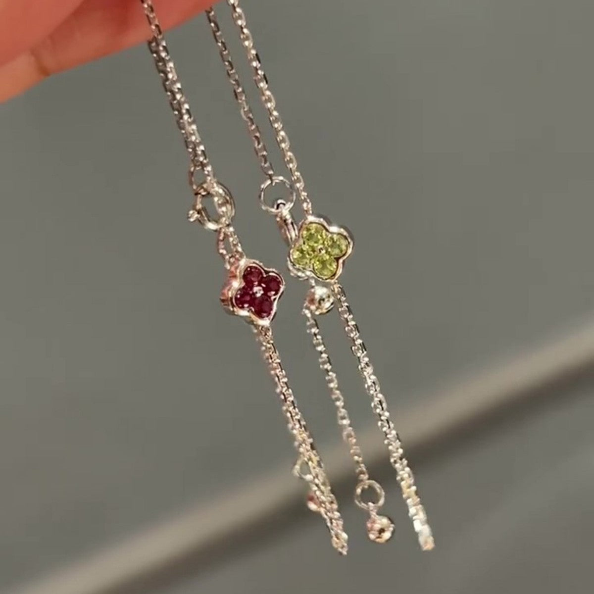 Red and green cz clover sterling silver chain bracelets held by fingers demonstrating premium wholesale quality