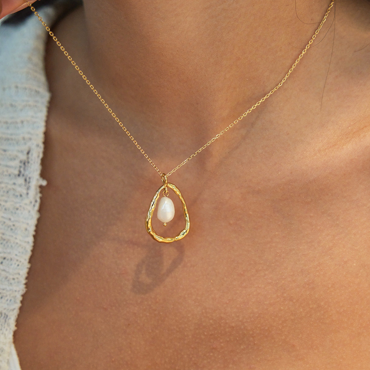 Front view of a gold stainless steel necklace with suspended freshwater pearl pendant