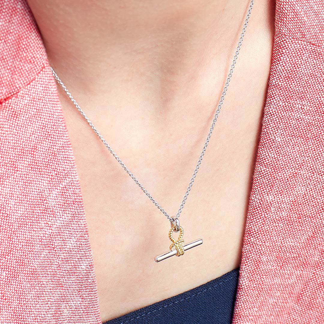 minimalist knot bar pendant necklace with two tone silver and gold design worn on collarbone