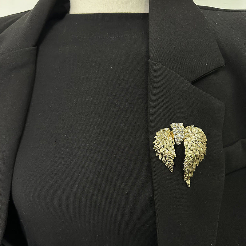 Gold crystal angel wings brooch styled on a black blazer lapel