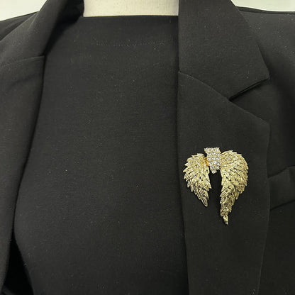 Gold crystal angel wings brooch styled on a black blazer lapel
