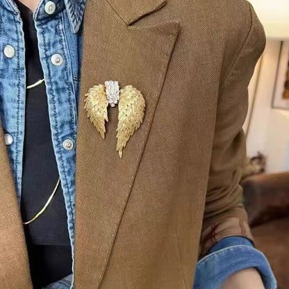French vintage gold angel wing brooch worn on a brown coat