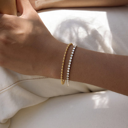 Gold double row cubic zirconia tennis bracelet worn on the wrist for layered styling

