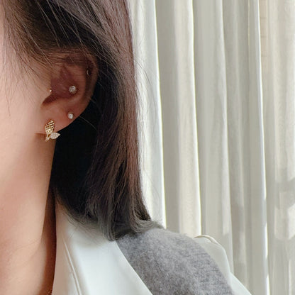 Woman wearing 18K gold plated leaf huggie earrings crafted from S925 sterling silver with cubic zirconia accents