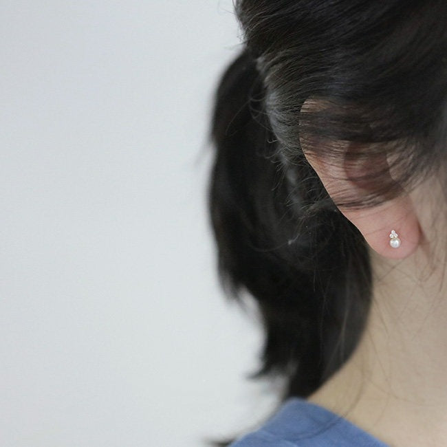 Woman wearing 14K gold plated pearl stud earrings crafted from S925 sterling silver with cubic zirconia accents