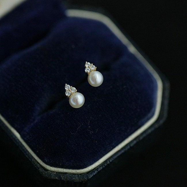 14K gold plated pearl stud earrings with cubic zirconia accents displayed in a jewelry box