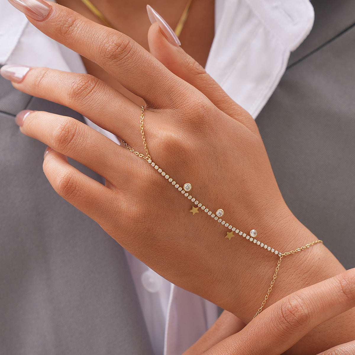 Front view of a gold cubic zirconia hand chain bracelet with star charms and finger loop