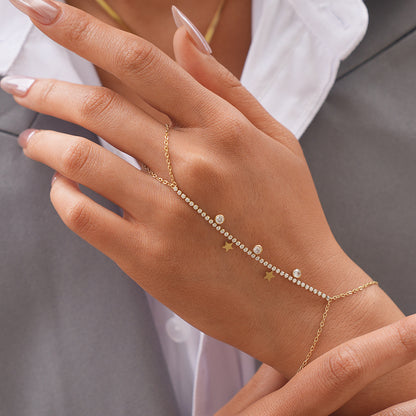 Front view of a gold cubic zirconia hand chain bracelet with star charms and finger loop