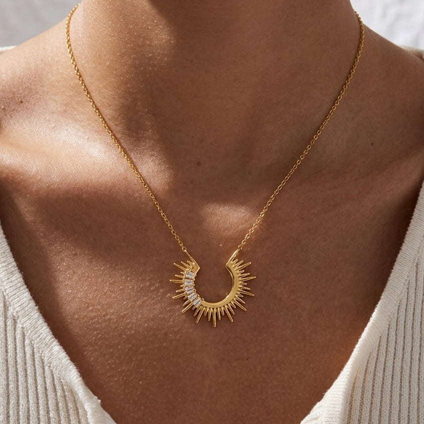 Gold celestial sunburst crescent necklace worn as a statement pendant