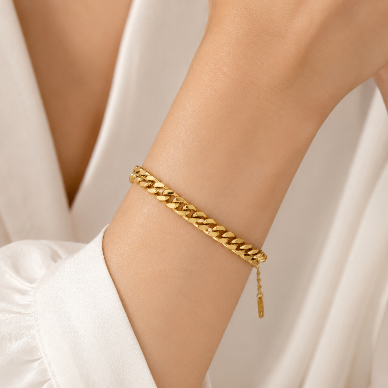 Polished gold titanium steel curb chain bracelet styled with a white blouse