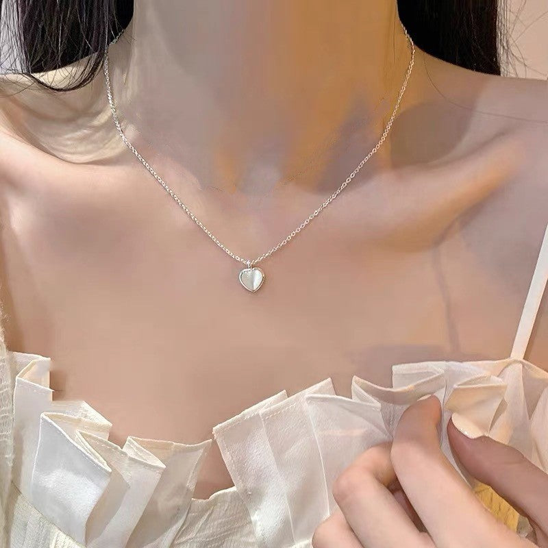 Model wearing S925 silver cat's eye heart necklace for an elegant minimalist clavicle chain style.