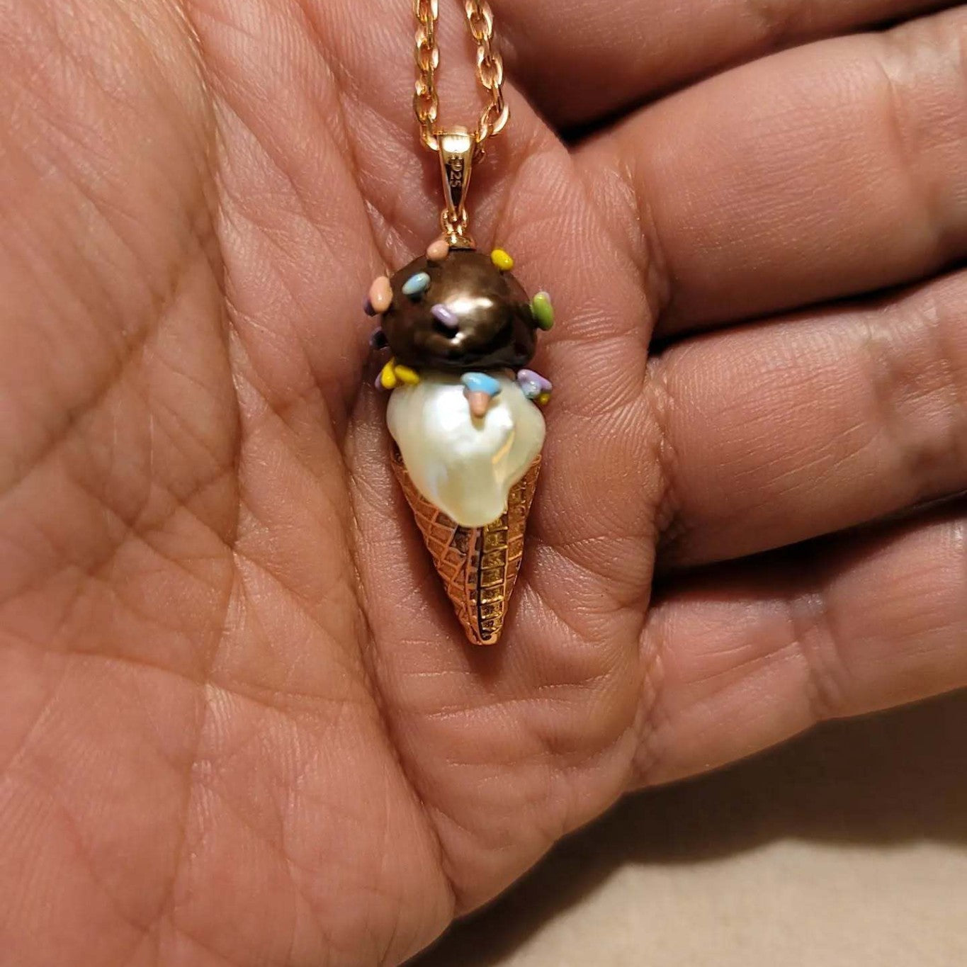 hand holding ice cream cone pendant necklace with pearl scoop and colorful sprinkles