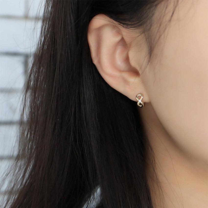 Woman wearing minimalist infinity earrings in S925 sterling silver with 18K gold plated finish