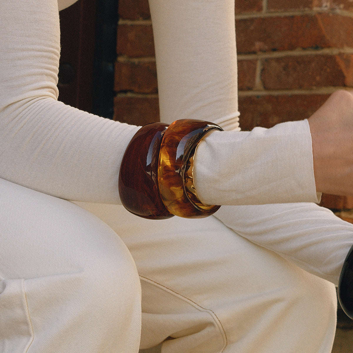 Model wearing brown tone wide resin bangles on wrist