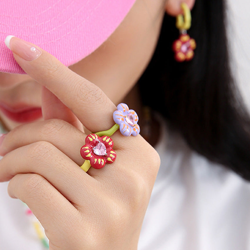 Model wearing colorful floral enamel rings with pink zircon center stones