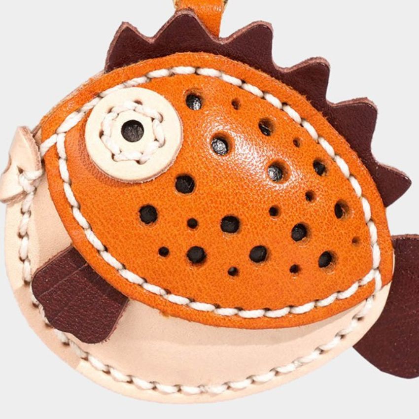 detail view of kawaii pufferfish animal keychain in orange and beige leather – artisan bag charm for handbags or car use