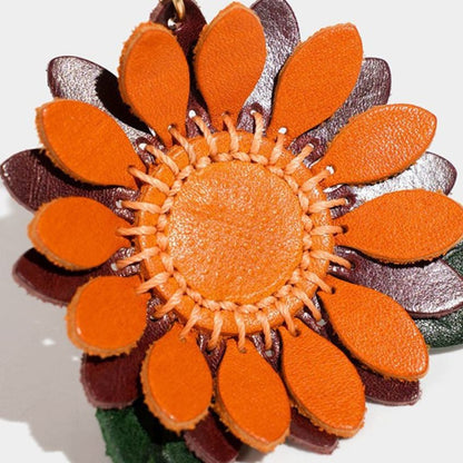 Close-up of handcrafted sunflower keychain in genuine leather, detailed orange petals and green leaf for fashion accessories