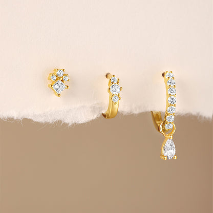 Wholesale product display of three gold S925 silver earrings including star engraved hoops and sparkling flower stud.