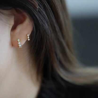 Woman wearing S925 sterling silver 14K gold plated triple cubic zirconia huggie earrings