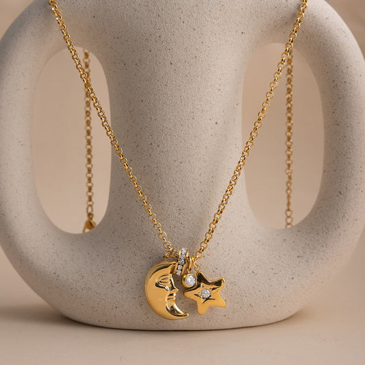 Gold tone stainless steel necklace with crescent moon face charm star pendant and crystal accents on display