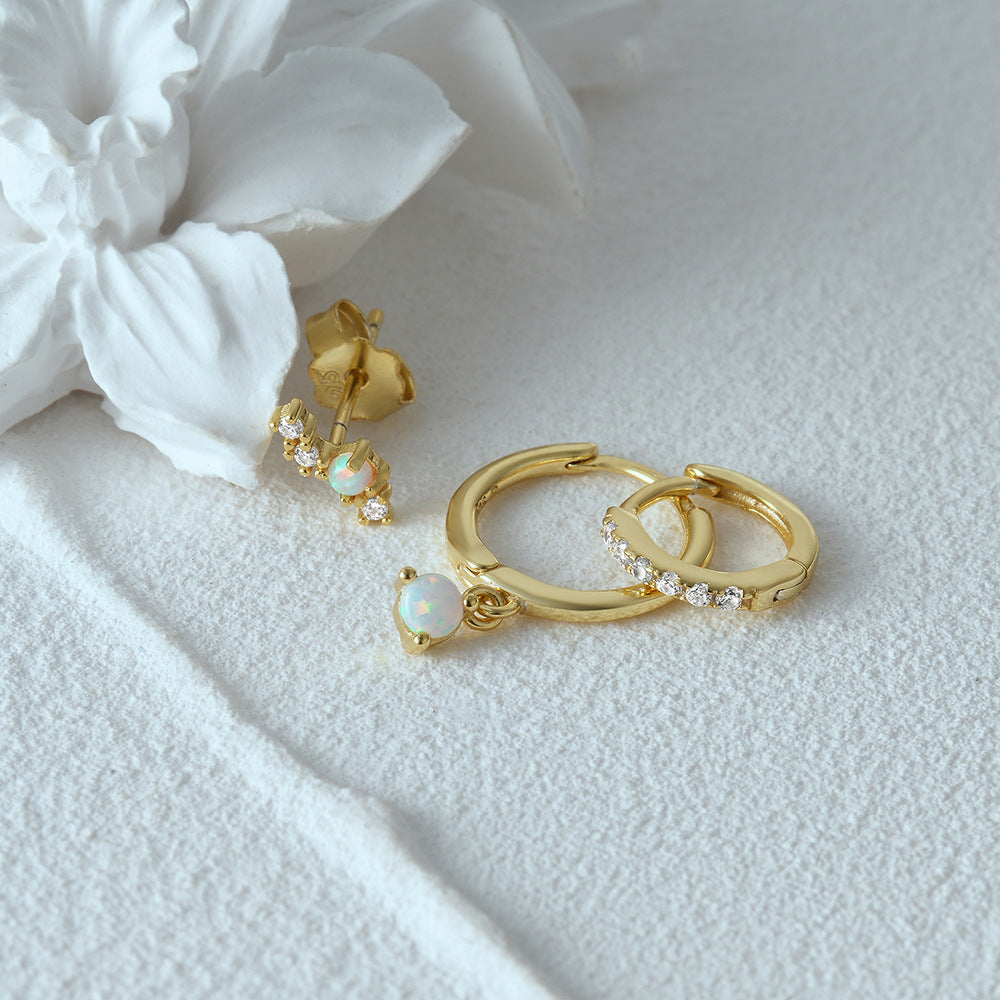 Close up of three unique gold earrings including an opal stud and shimmering hoop earrings for boutique wholesale.