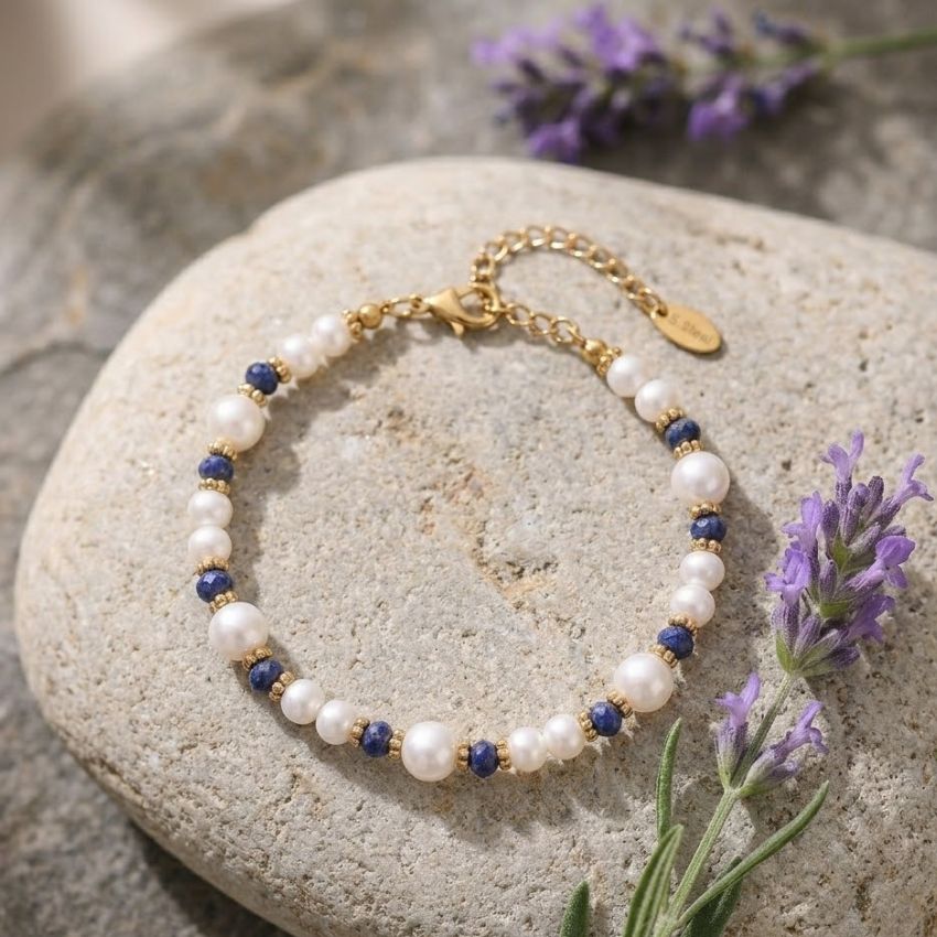 Pearl beaded bracelet with blue stone accents gold tone spacers flat lay