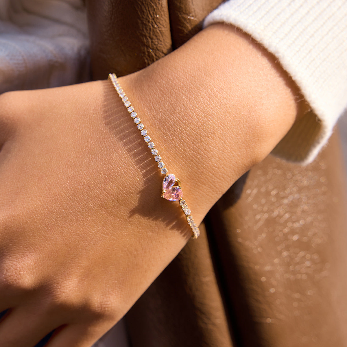 Model wearing gold stainless steel tennis bracelets with pink heart zircon accents