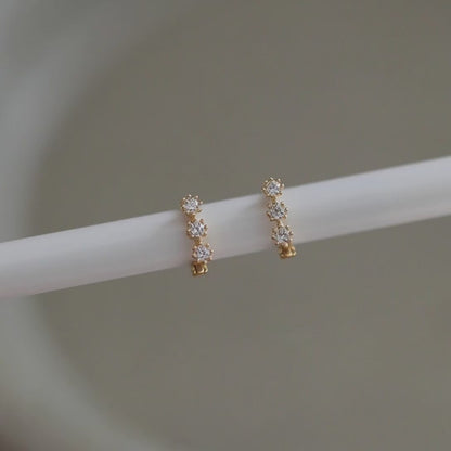 Rotating view of S925 sterling silver 14K gold plated triple cubic zirconia huggie earrings for wholesale jewelry sourcing and resale collections
