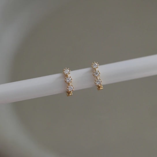 Rotating view of S925 sterling silver 14K gold plated triple cubic zirconia huggie earrings for wholesale jewelry sourcing and resale collections