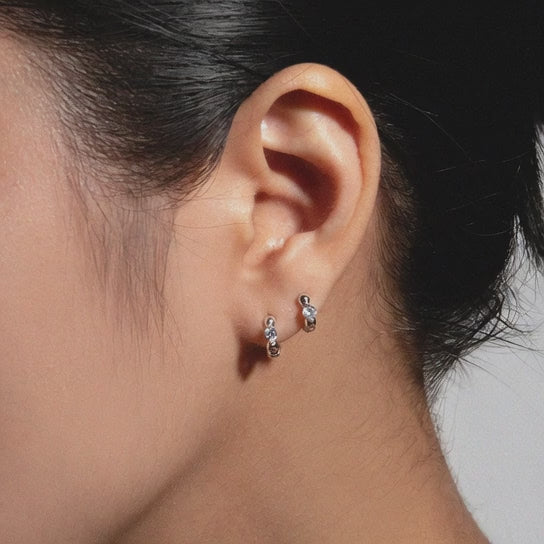 Rotating display of S925 sterling silver huggie earrings with cubic zirconia and 18K gold plated finish for wholesale jewelry sourcing and resale buyers