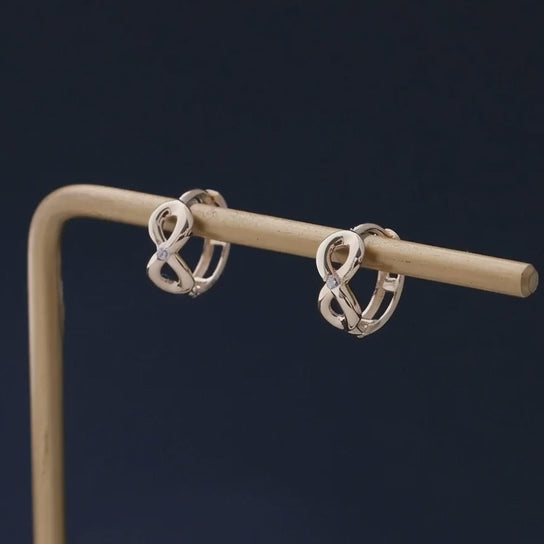 Rotating display of S925 sterling silver infinity earrings with 18K gold plating for wholesale jewelry sourcing and boutique resale collections