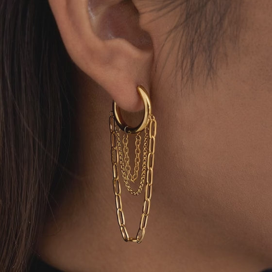 Gold tone hoop earrings with layered chain tassels displayed 