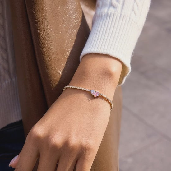 Gold stainless steel tennis bracelet with pink heart zircon showcased on wrist in motion