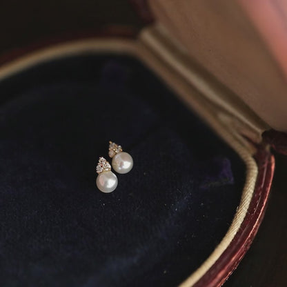 Rotating display of 14K gold plated pearl stud earrings crafted from S925 sterling silver with shell pearls and cubic zirconia accents for wholesale jewelry buyers
