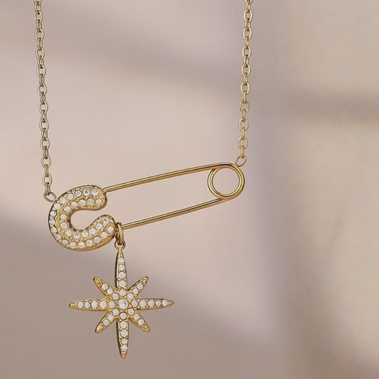 close up video of gold stainless steel safety pin necklace with cubic zirconia star pendant