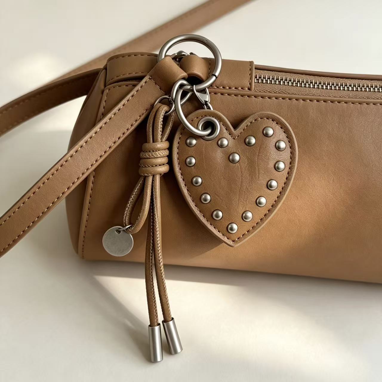 Taupe PU leather studded heart charm attached to a brown handbag
