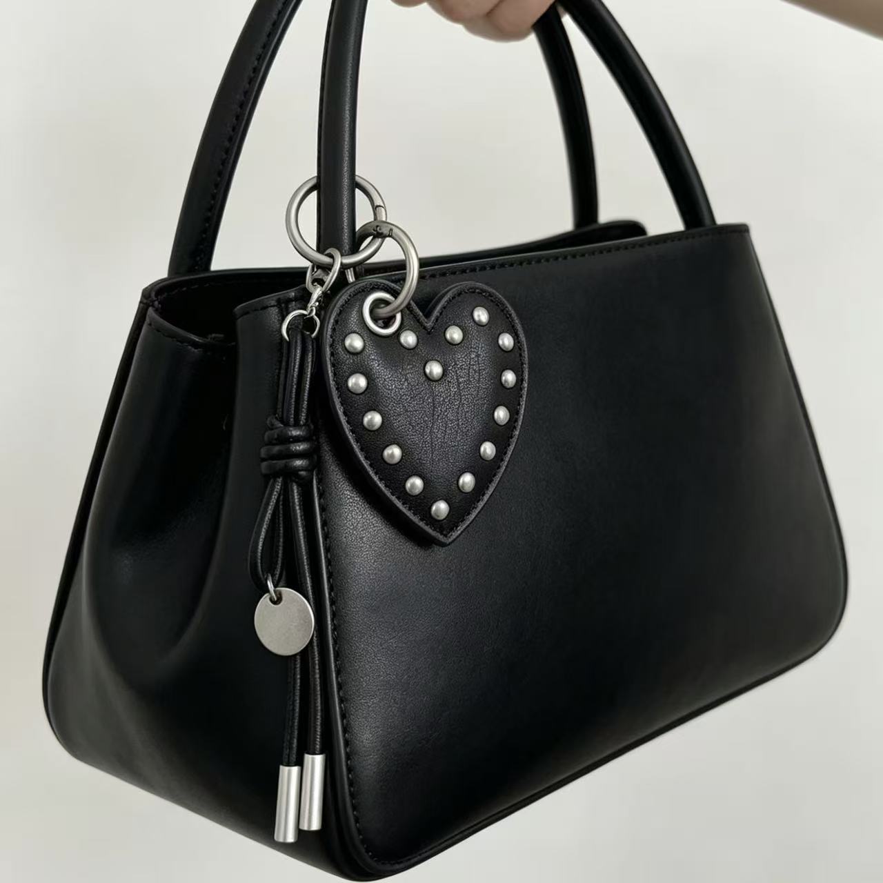 Black PU leather heart charm with metal studs on a black handbag