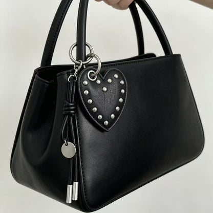 Black PU leather heart charm with metal studs on a black handbag