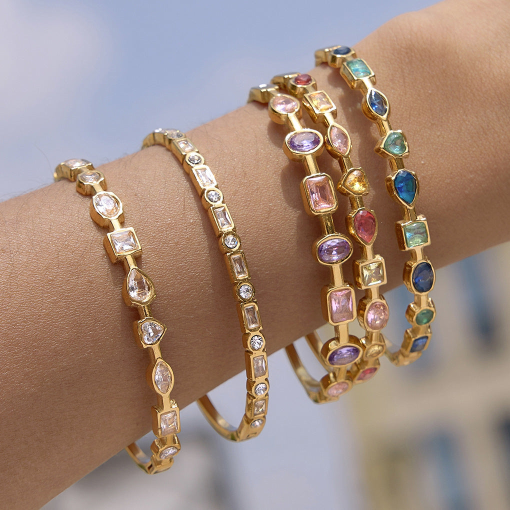 Stacked gold bangles with colorful mixed shape gemstone details