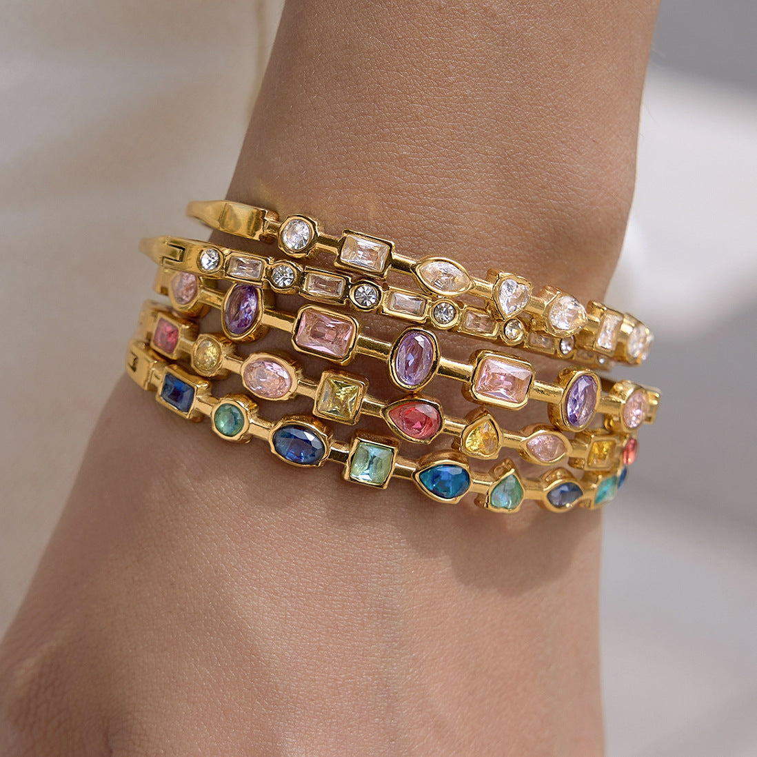 Colorful gemstone gold bangles displayed in multiple selectable designs