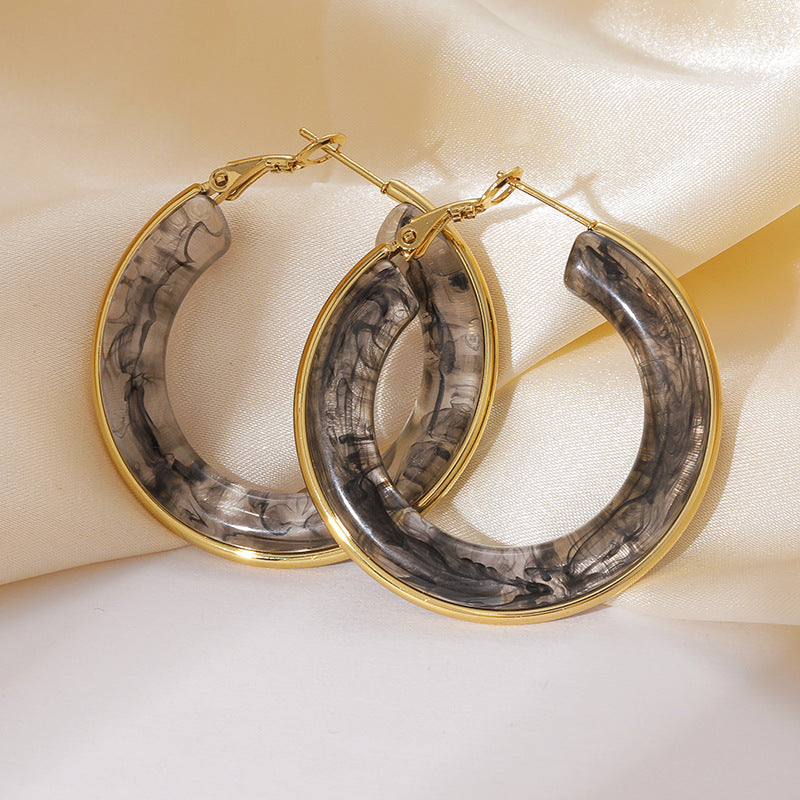Closeup of gray resin hoop earrings with polished gold tone hoop frame for boutique resale