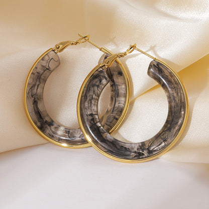 Closeup of gray resin hoop earrings with polished gold tone hoop frame for boutique resale