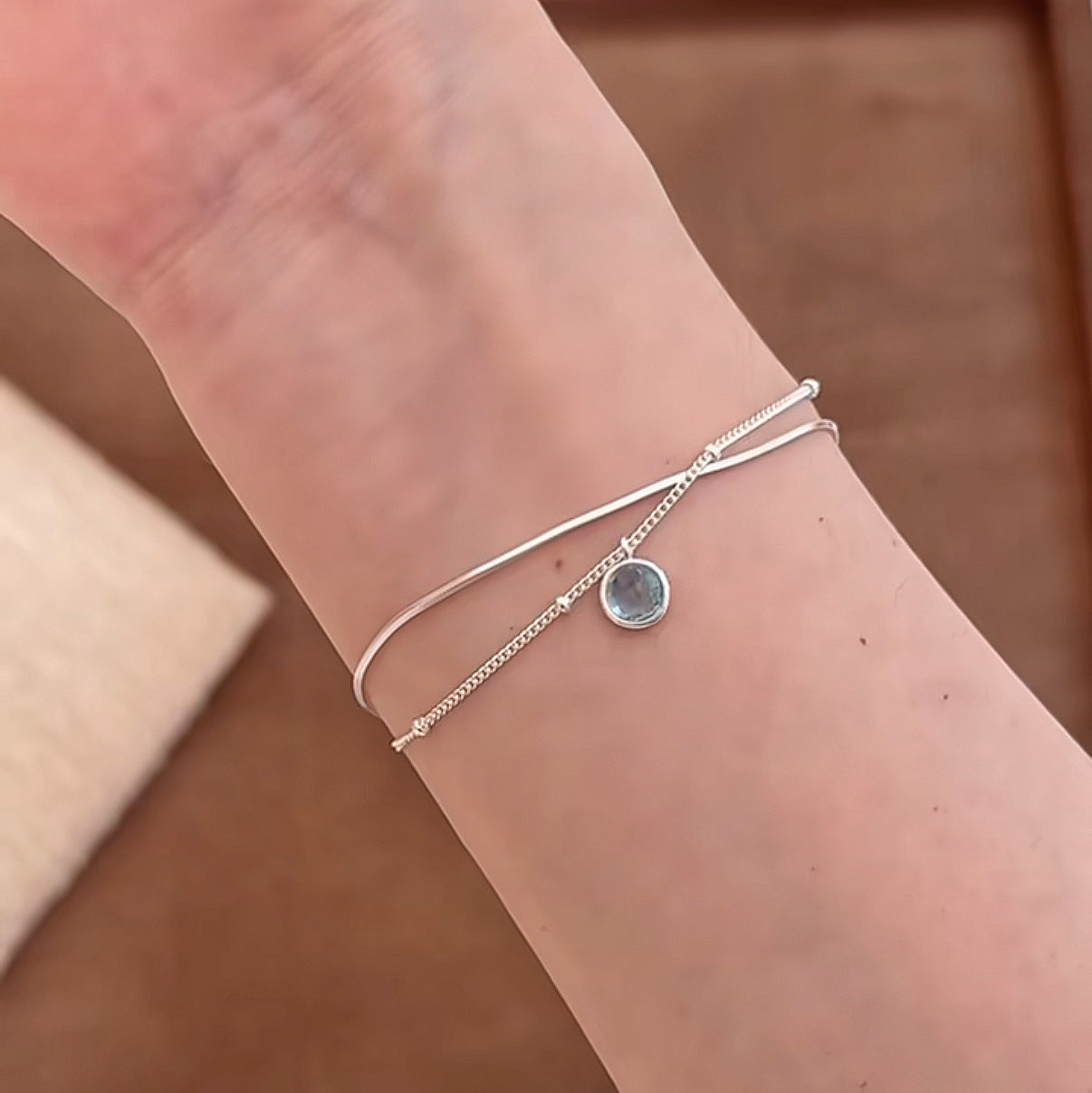 Close view of an S925 silver double chain bracelet with a round blue aquamarine pendant
