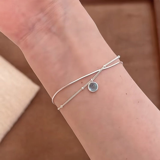 Close view of an S925 silver double chain bracelet with a round blue aquamarine pendant