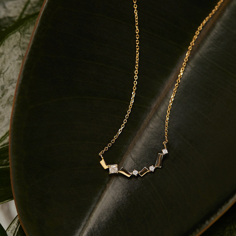 Wholesale S925 18K gold plated bar zircon necklace displayed on dark green leaf
